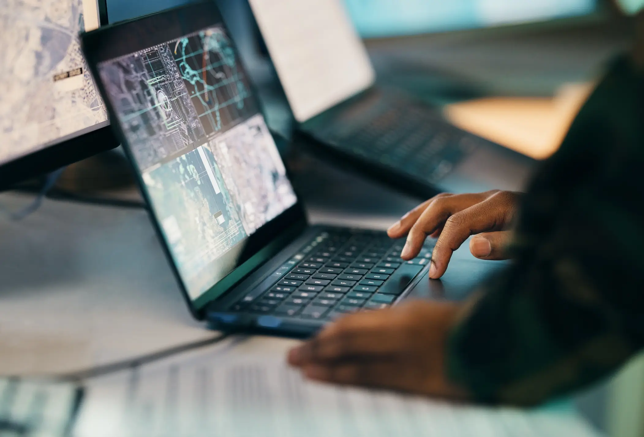 Person typing on laptop with maps displayed